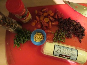 Black pepper, red pepper flakes, basil, pine nuts, capers, kalamata olives, black tomatoes, orange cherry tomatoes, and goat cheese.