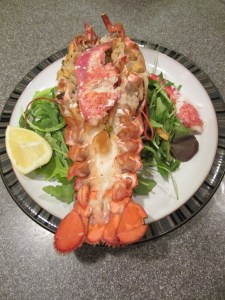 Final stuffed lobster with claw meat on top and lemon on the side.
